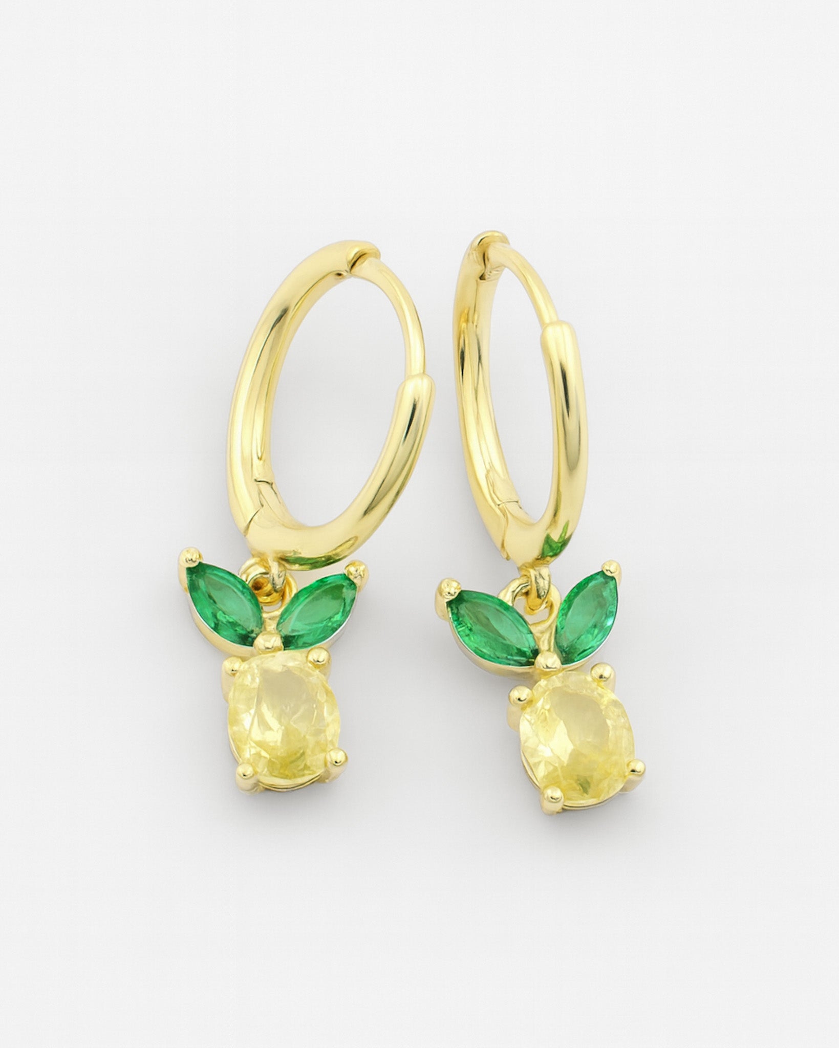 Gold earrings with green gemstones on a white background