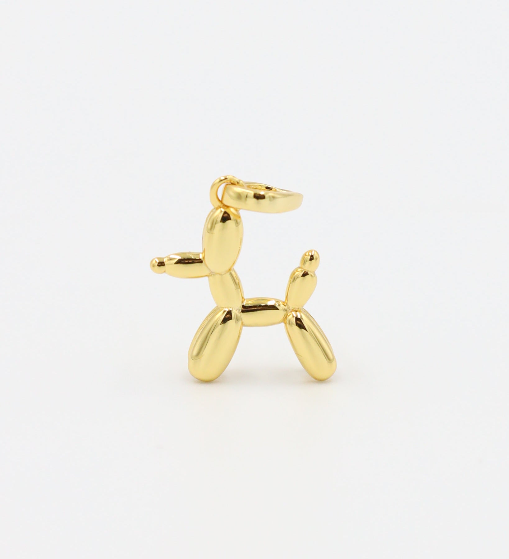 Standing view of a gold-plated balloon dog pendant made from sterling silver.

