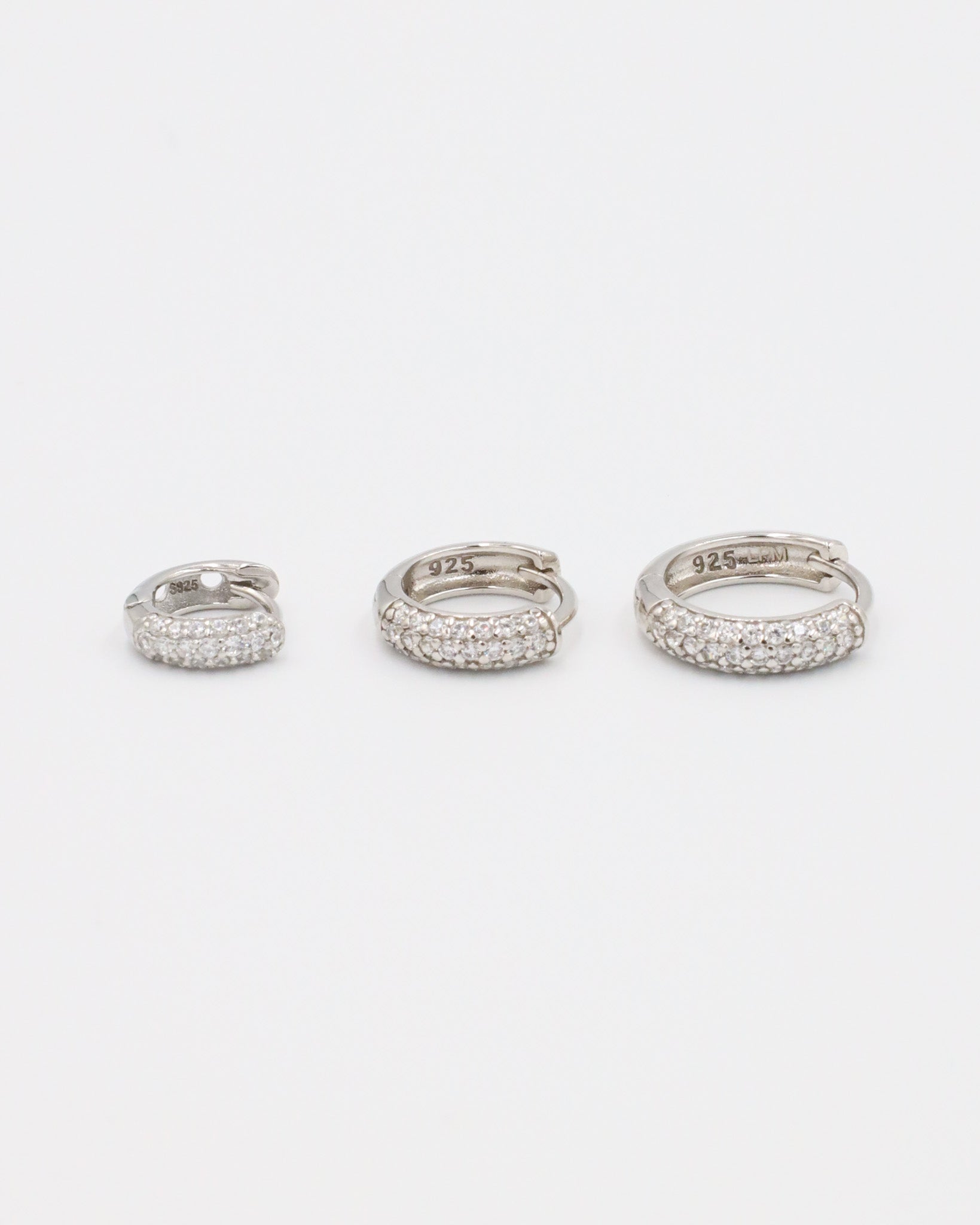 Three sizes of Billie hoop earrings in silver with zirconia stones, displayed from a top view. Sizes shown: S, M, and L.