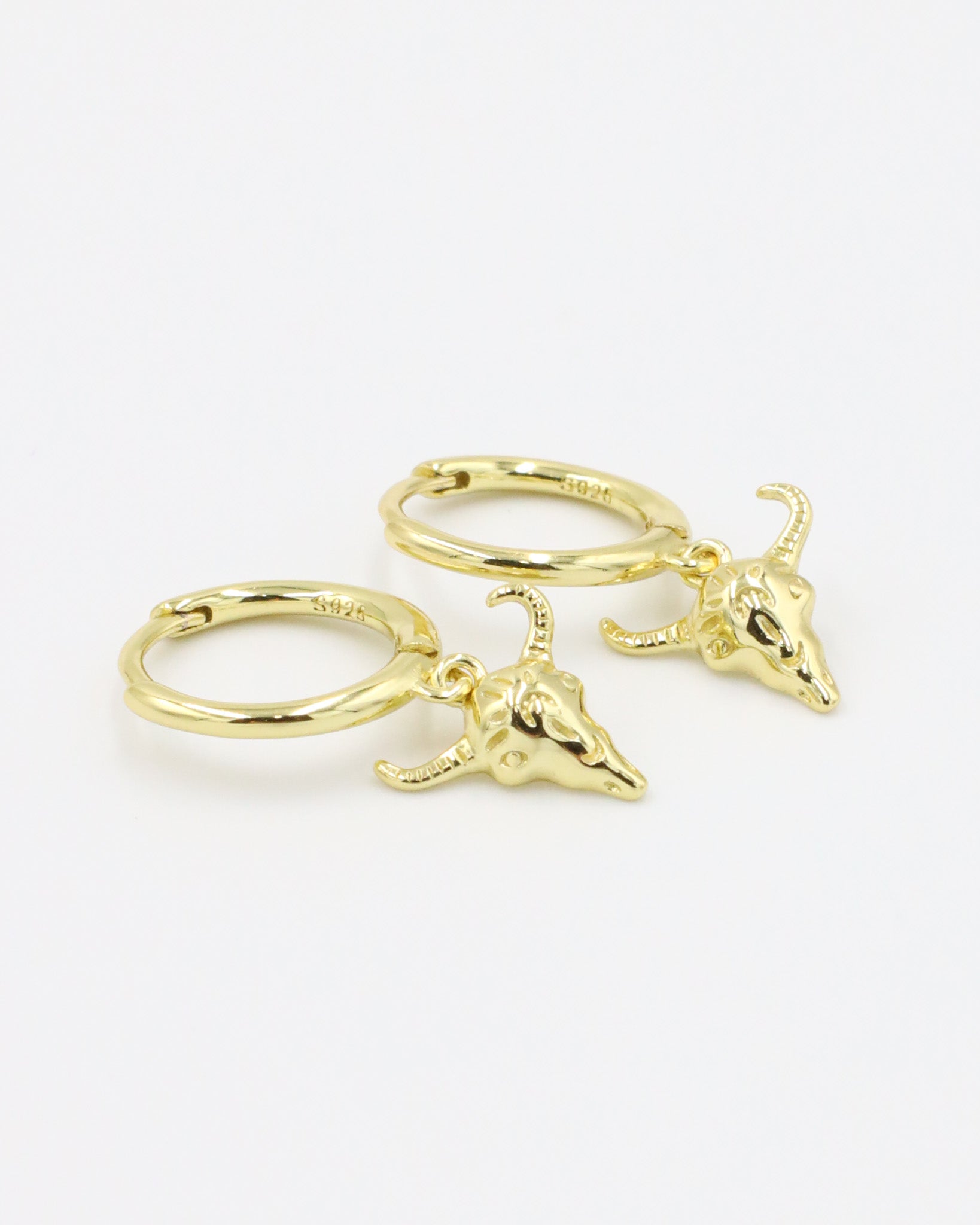 A pair of gold-plated sterling silver hoop earrings featuring bull skull charms.