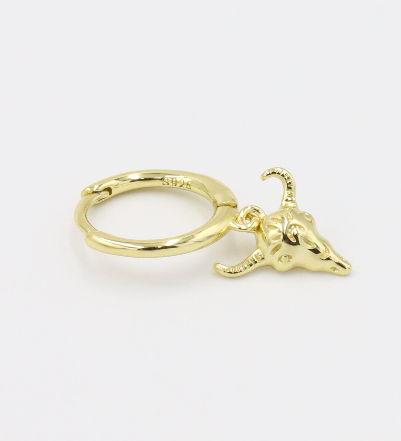 A single gold-plated sterling silver hoop earring with a bull skull charm.