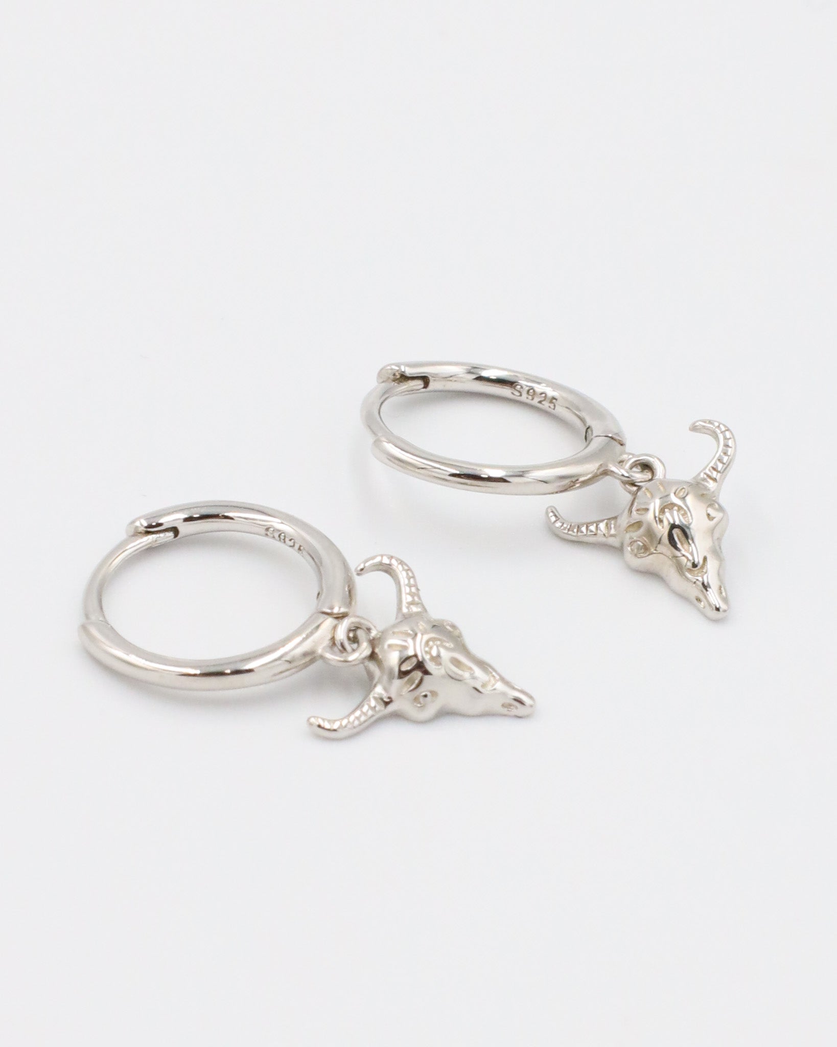 Pair of sterling silver hoop earrings with detailed bull skull charms.