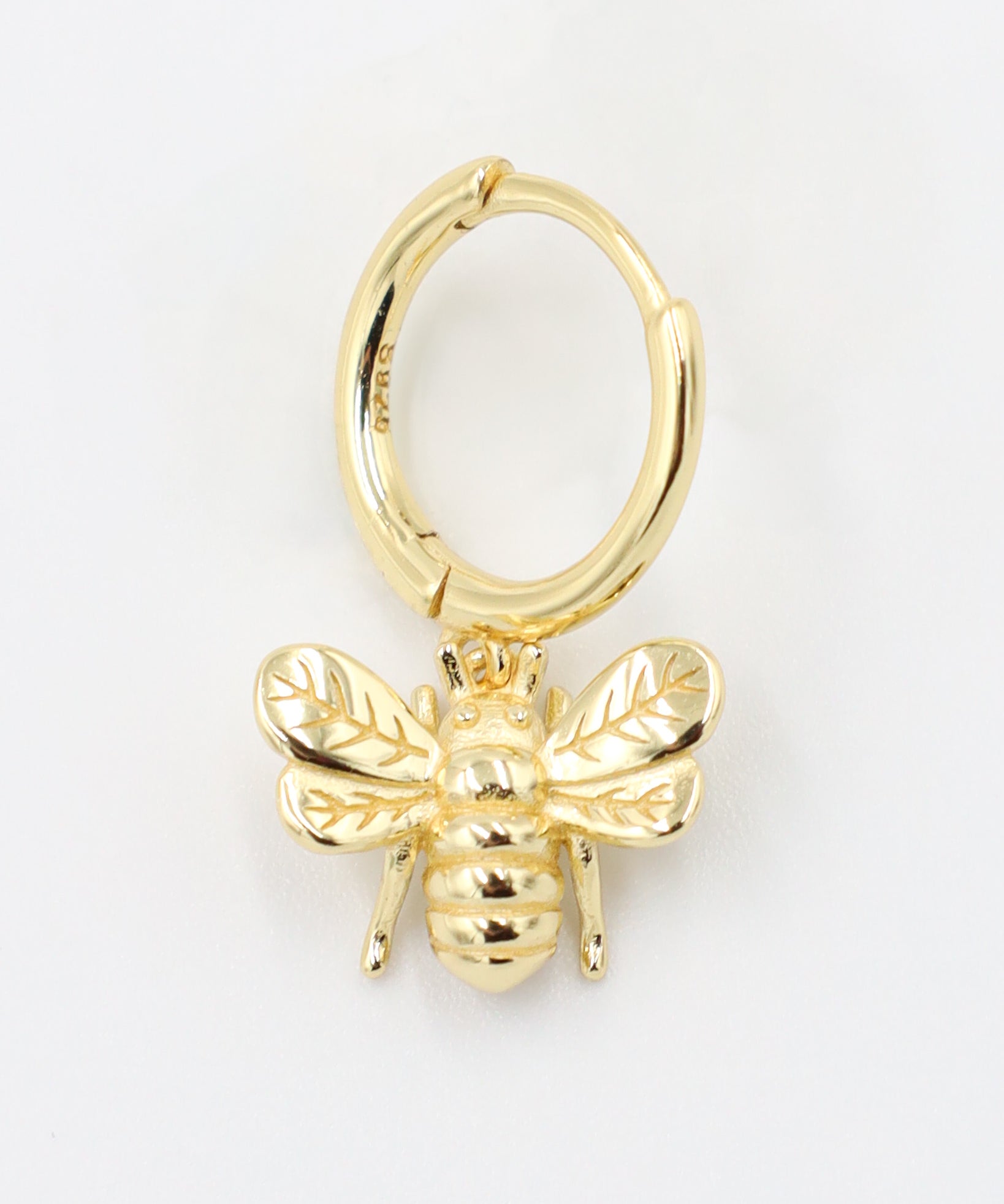 Single gold-plated sterling silver hoop earring with a bee charm, side view.