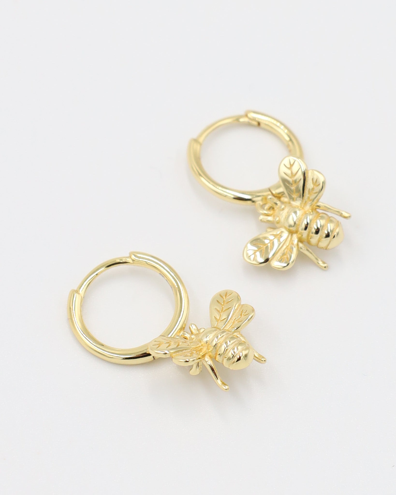 Gold-plated sterling silver hoop earrings with a bee charm, shown as a pair.