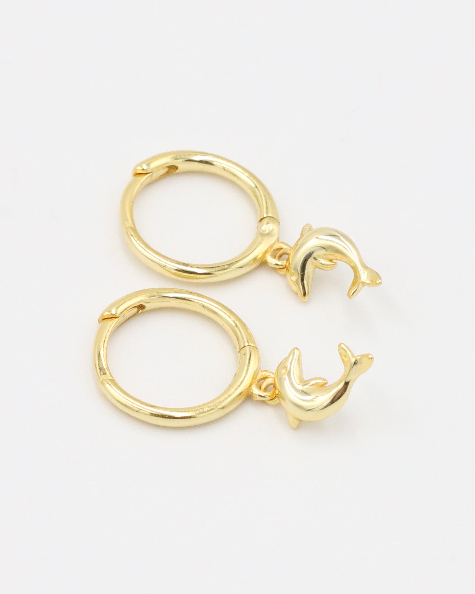 Pair of gold-plated sterling silver hoop earrings with dolphin charms, side view.
