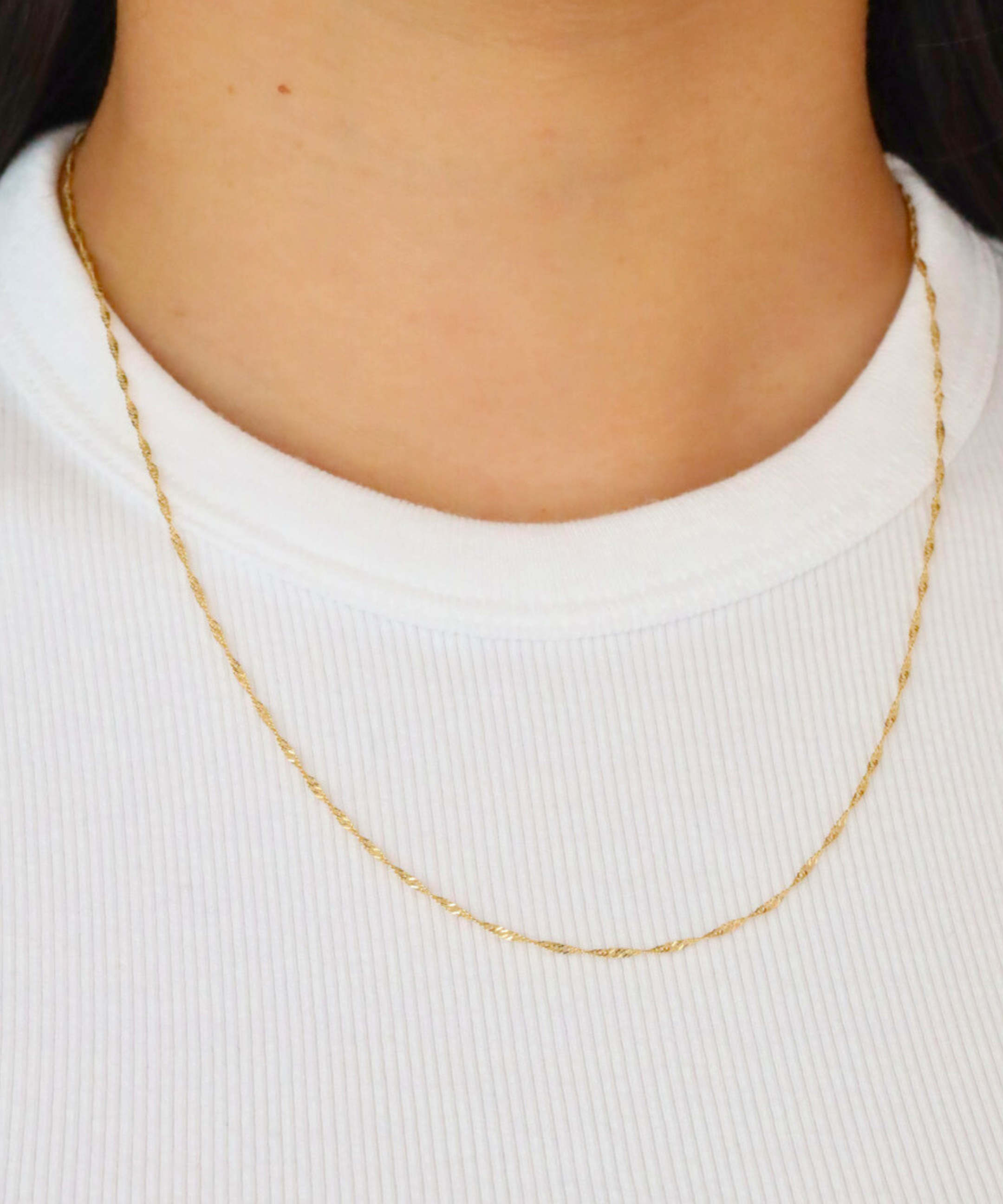 Jamie Gold necklace worn on a model, showcasing the elegant and delicate twisted rope chain on a white shirt.