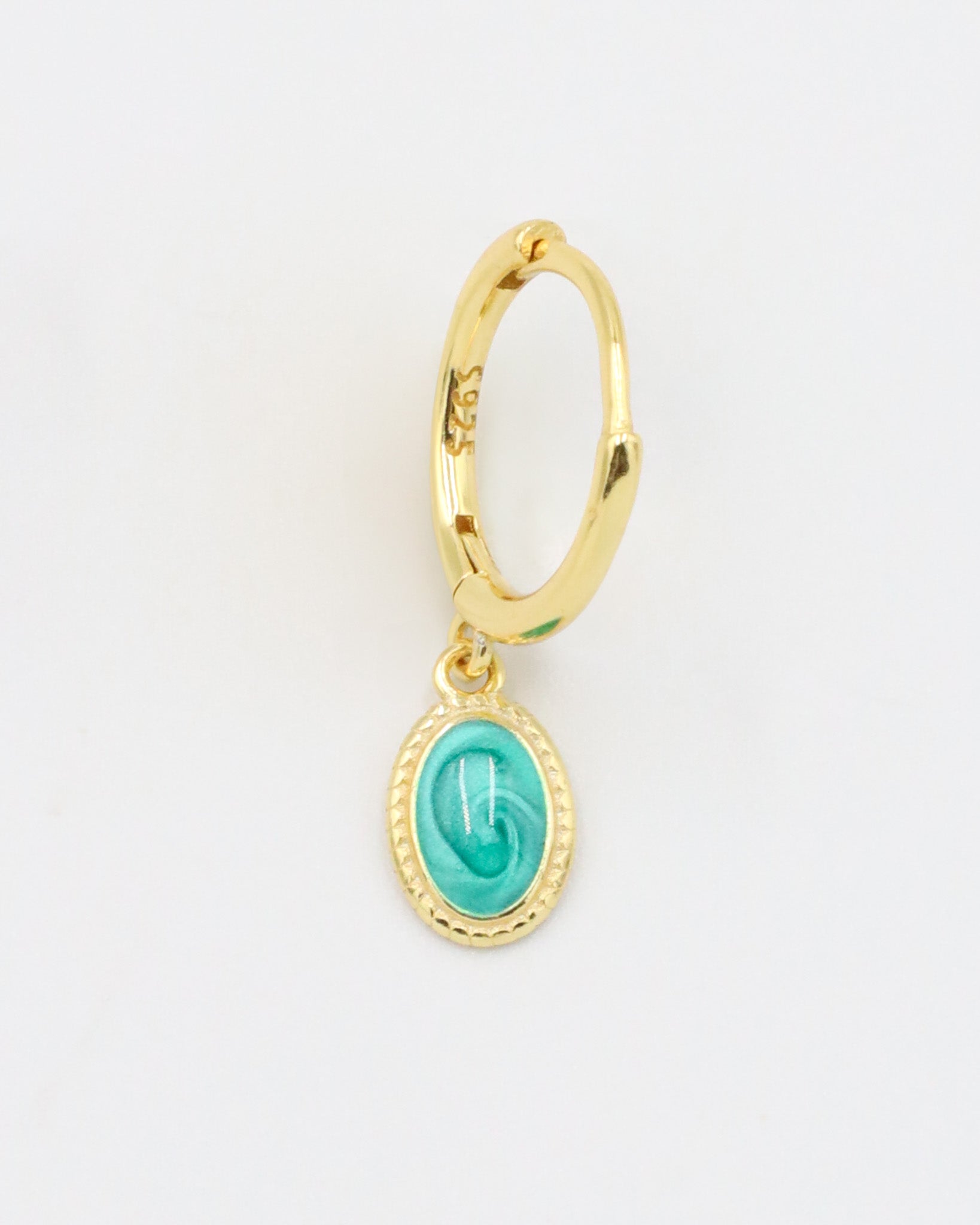 A close-up of a single gold-plated sterling silver hoop earring with an oval turquoise charm, displayed from the front.
