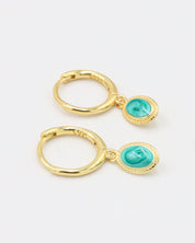 A pair of gold-plated sterling silver hoop earrings featuring an oval-shaped turquoise stone charm, displayed from the front.
