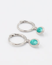 Pair of Josefine Silver hoop earrings with a turquoise oval pendant on sterling silver hoops.
