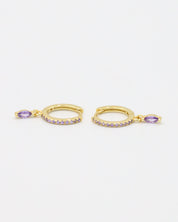 A pair of Kyiomi Purple earrings made from gold-plated sterling silver, featuring small purple zirconia stones along the hoop and a dangling marquise-shaped purple zirconia stone.