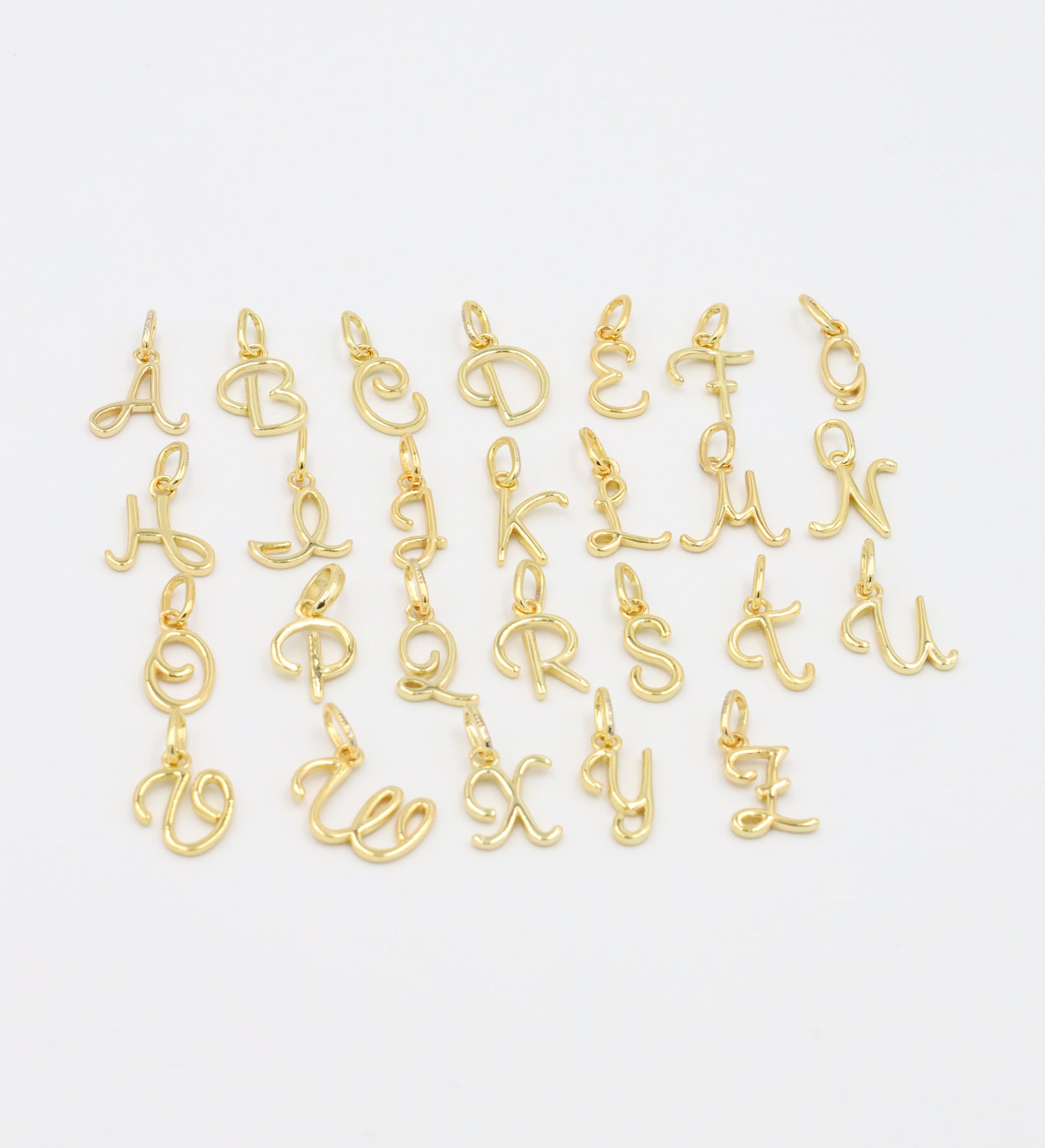Close-up of gold-plated letter curve pendants in various alphabetical characters.