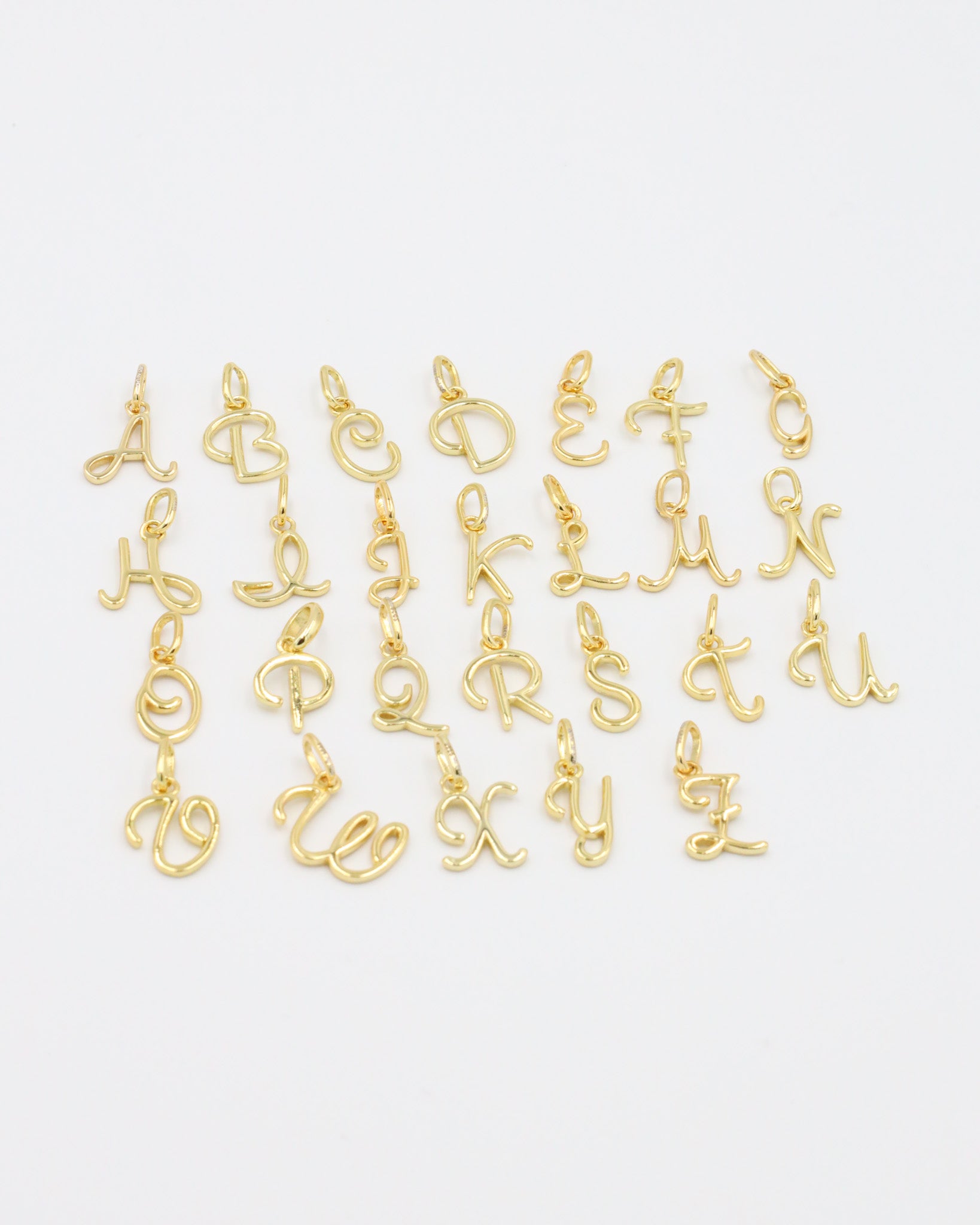 Close-up of gold-plated letter curve pendants in various alphabetical characters.