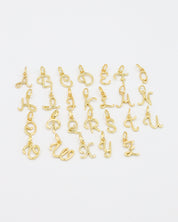 Close-up of gold-plated letter curve pendants in various alphabetical characters.