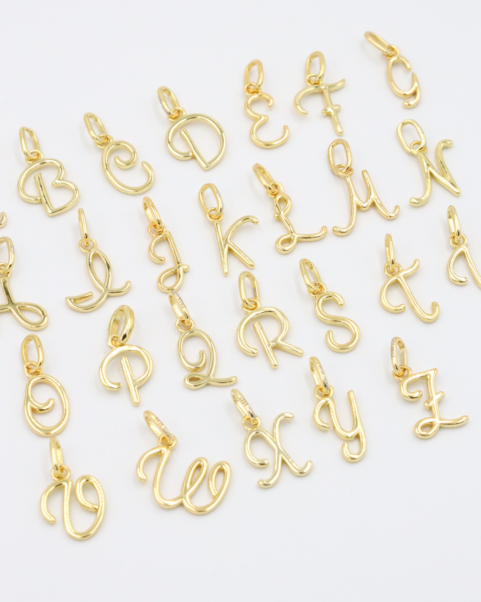 Gold-plated letter curve alphabet pendants arranged neatly for display.