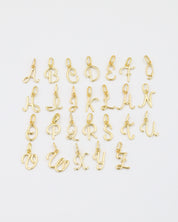 A set of gold-plated letter curve alphabet pendants spread flat in a display.