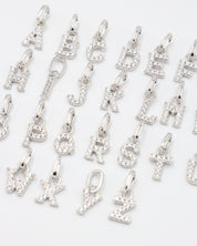 Close-up view of sterling silver alphabet letter pendants with zirconia stones.