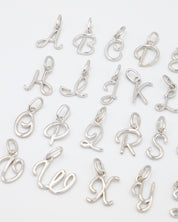 Close-up of rhodium plated 925 sterling silver letter curve pendants, showcasing details of the individual letters.