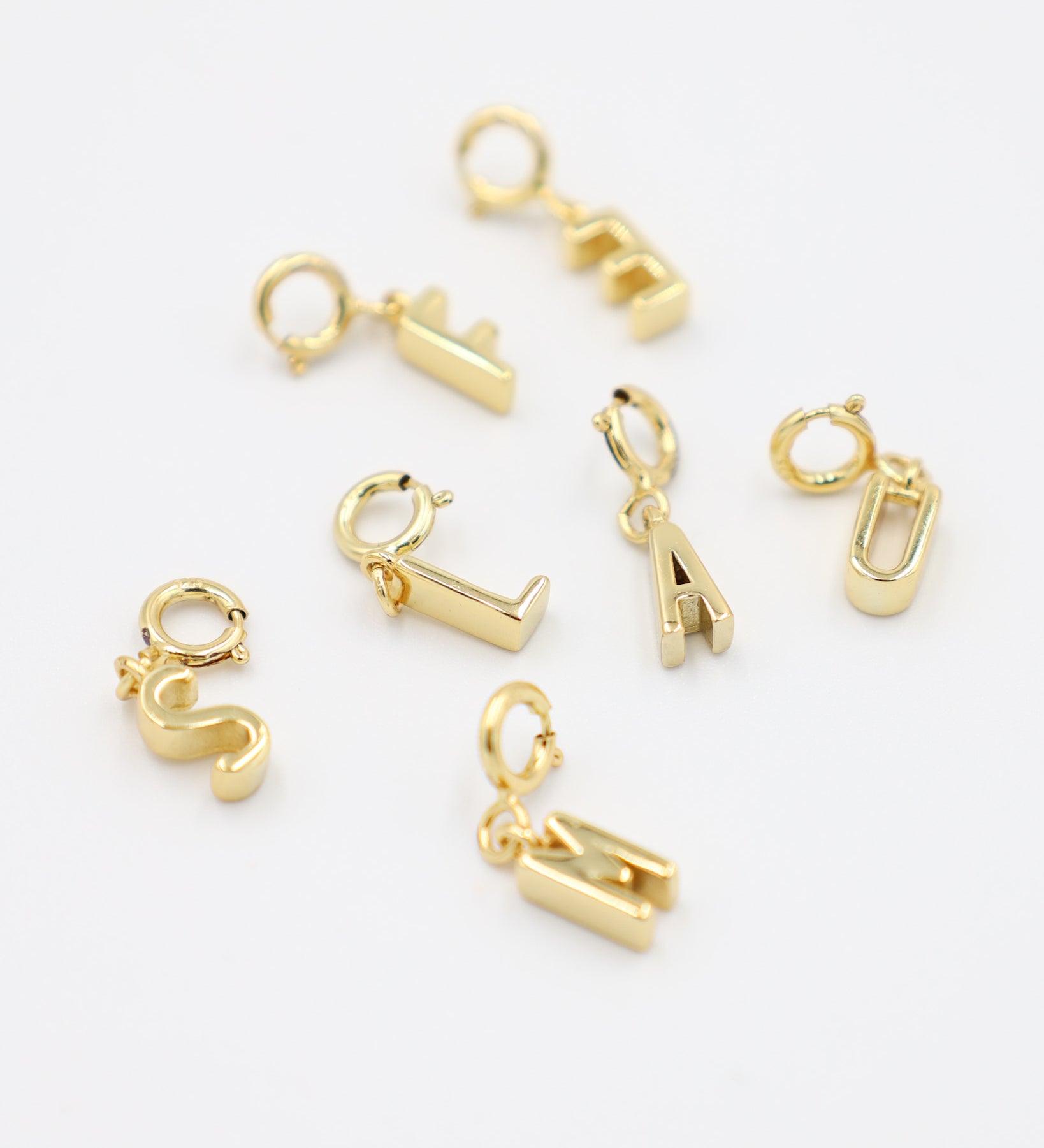 Gold-plated letter pendants with clasp, made from 925 sterling silver, displayed together in various letter designs. Each pendant can be easily attached to any chain necklace.