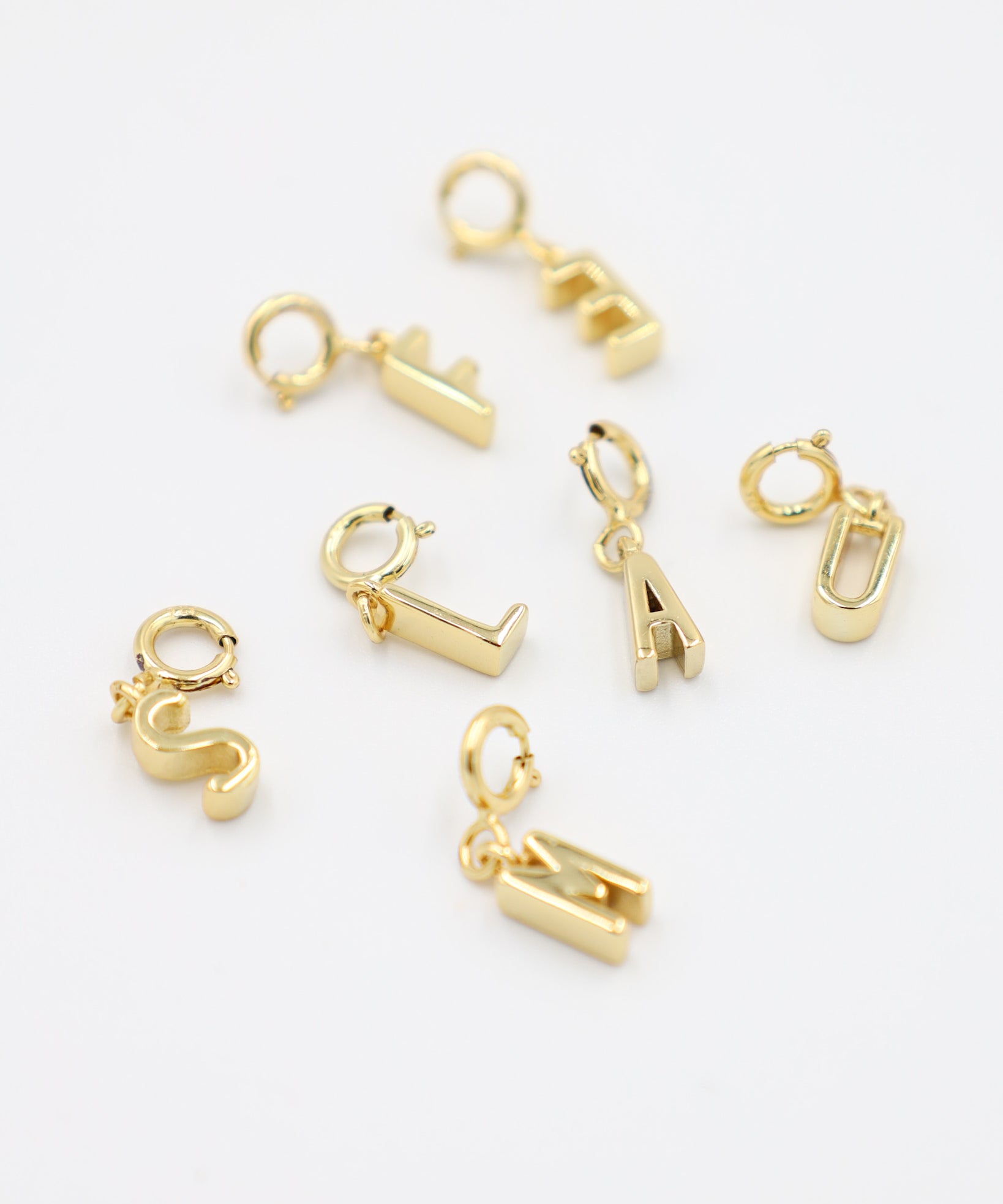 Gold-plated letter pendants with clasp, made from 925 sterling silver, displayed together in various letter designs. Each pendant can be easily attached to any chain necklace.