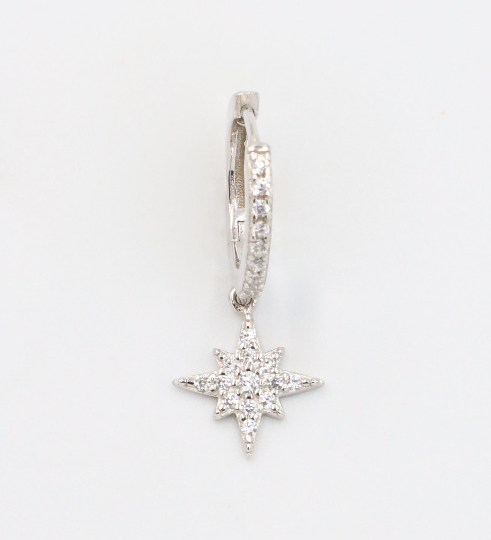 A single "Nova Silver" earring made from sterling silver, featuring cubic zirconia stones arranged in a star-shaped pendant with pave detailing on the hoop.
