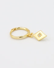 Single Patricia Gold earring featuring a starburst design with a zirconia center, hanging from a gold hoop.
