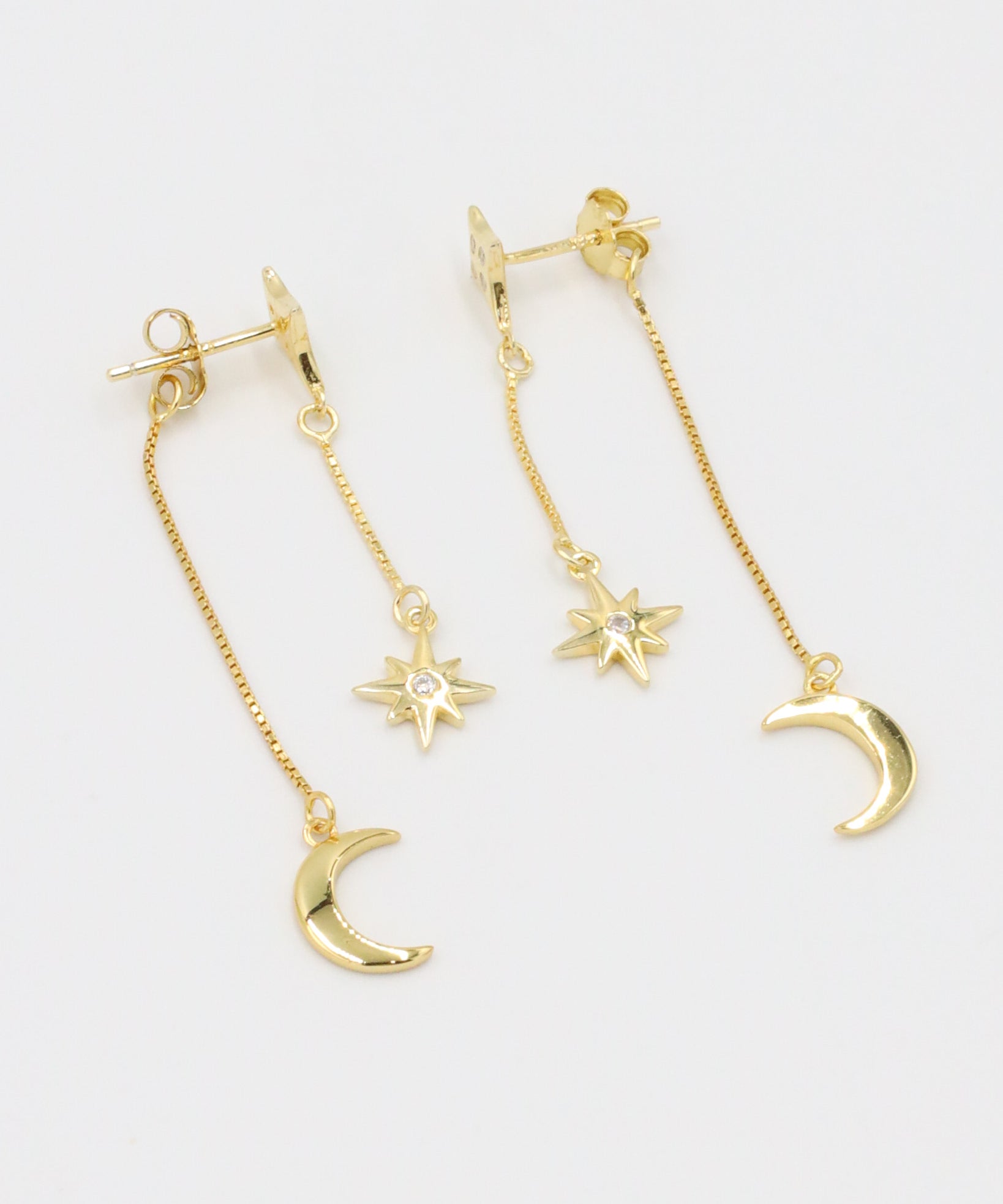 Pair of Reese gold-plated earrings featuring a crescent moon and star with a delicate chain, made from sterling silver.