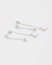 Elegant pair of Reese silver earrings in sterling silver, with moon and star charms on delicate chain drops.