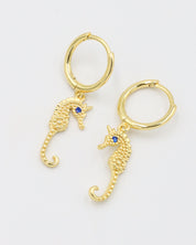 Pair of Seahorse Gold earrings made from gold-plated sterling silver, featuring seahorse charms with blue zirconia eyes.
