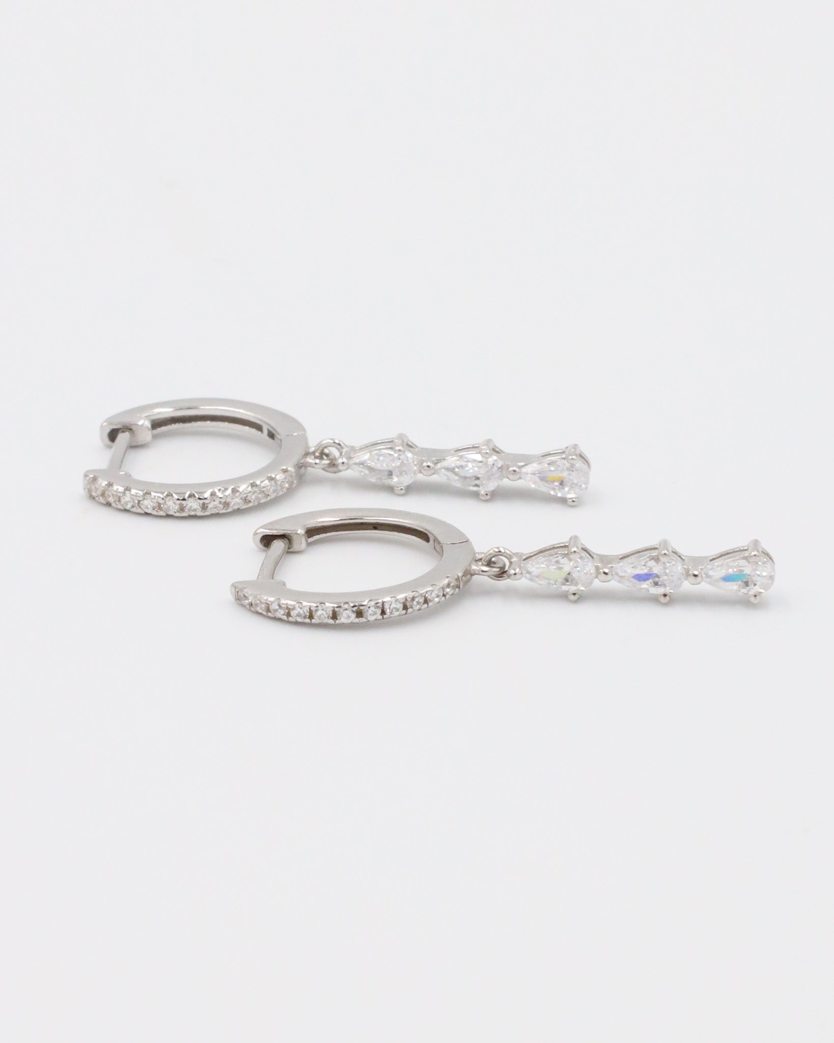 Side view of sterling silver drop earrings with a row of sparkling teardrop-shaped cubic zirconia stones.