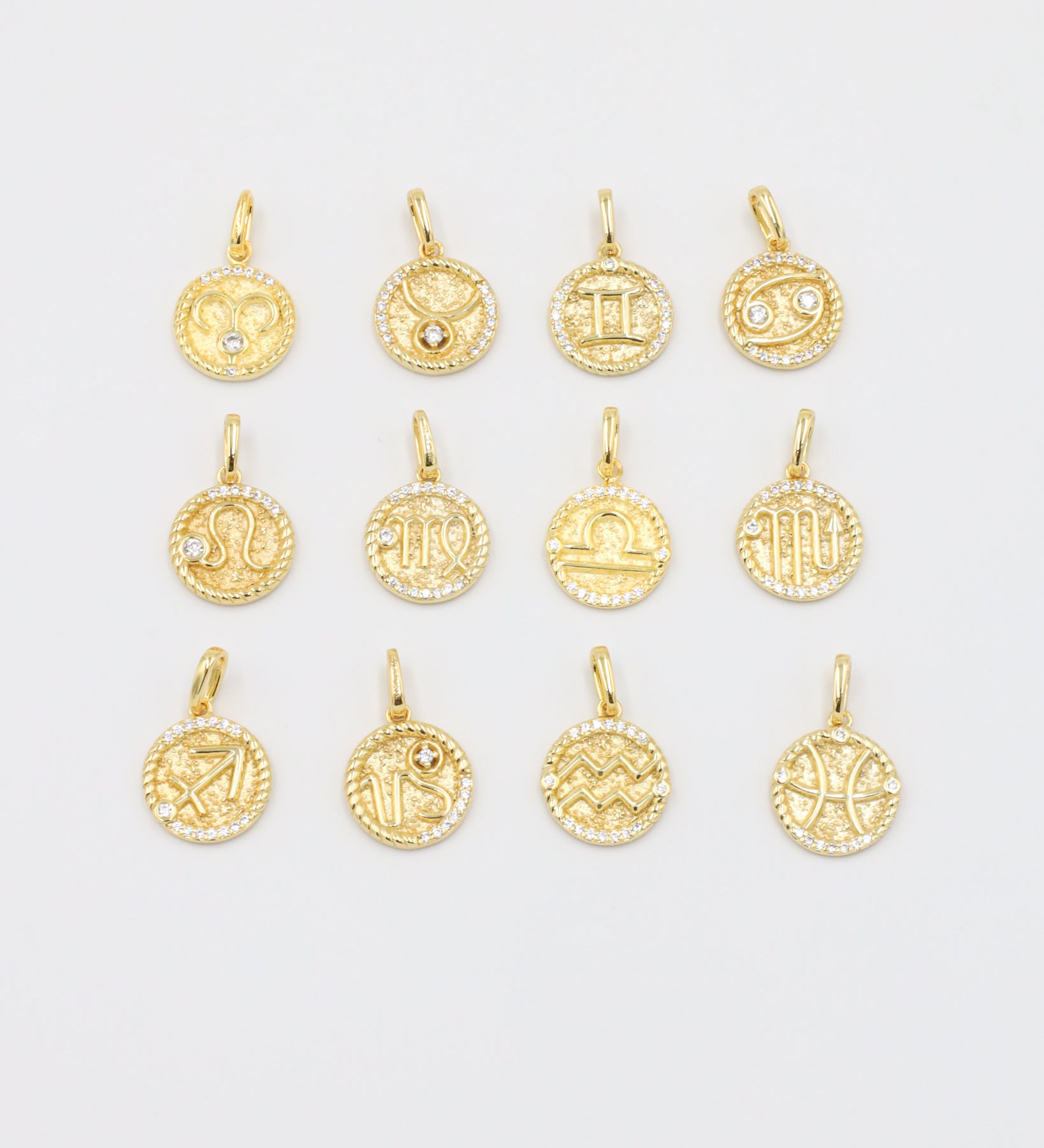 A collection of gold-plated sterling silver zodiac pendants with sparkling zirconia stones.