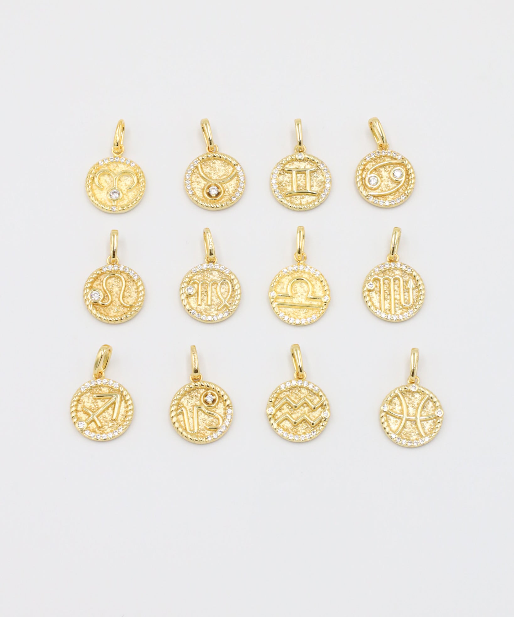 A collection of gold-plated sterling silver zodiac pendants with sparkling zirconia stones.