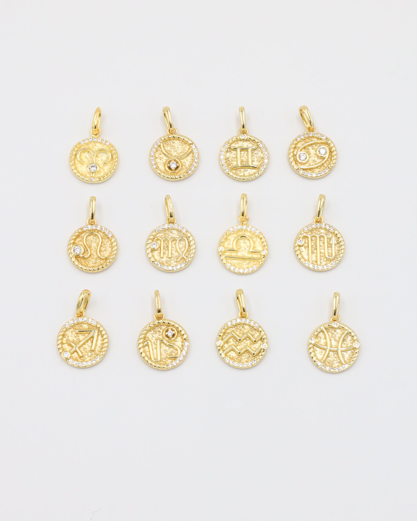 A collection of gold-plated sterling silver zodiac pendants with sparkling zirconia stones.