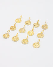 Gold-plated sterling silver zodiac pendants displayed at an angle with detailed sparkling zirconia stones.