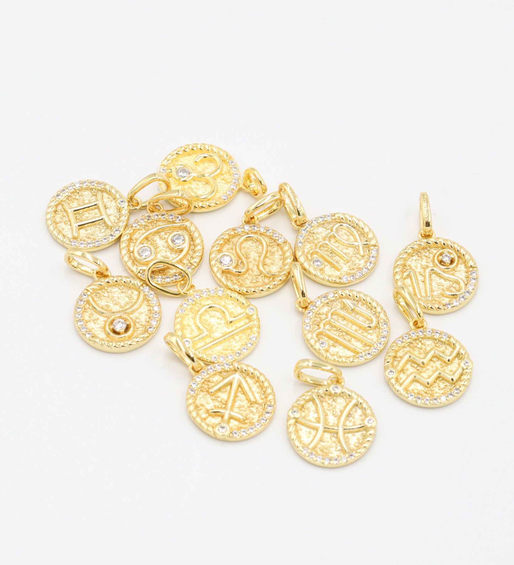 Assorted zodiac symbol pendants in gold-plated sterling silver featuring zirconia accents.
