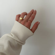 A gold-colored ring with multiple multicolored gemstones set close together worn on a hand.