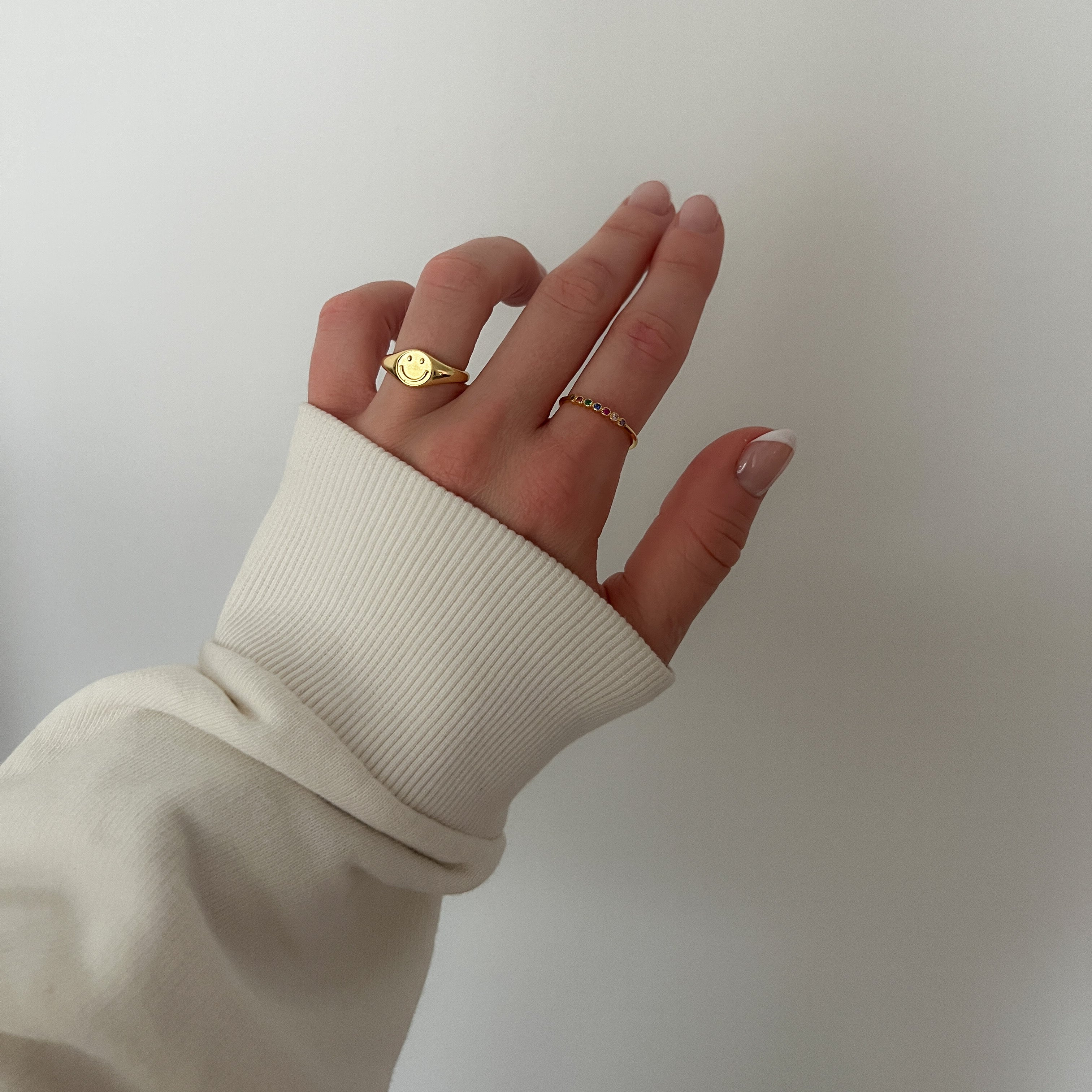 A gold-colored ring with multiple multicolored gemstones set close together worn on a hand.